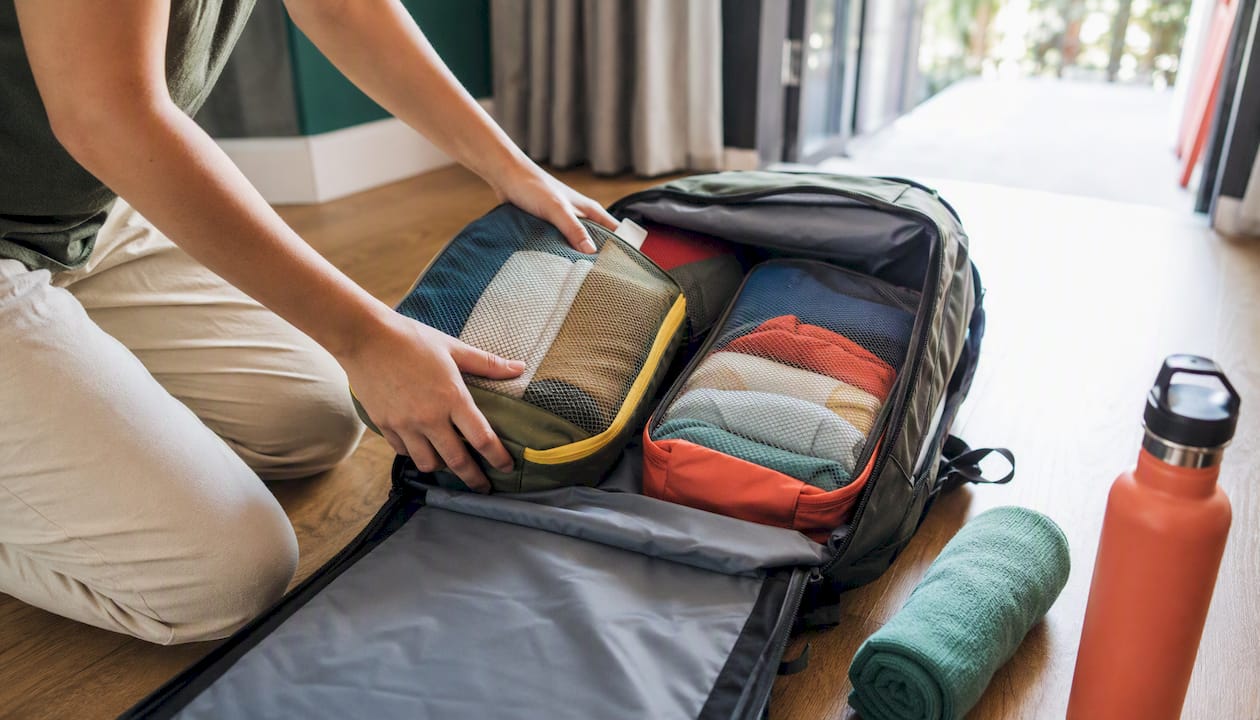 30+ Proven Ways to Save on Travel for Canadians 2026 Lizard's Lunch Overhead of hands packing compression cubes