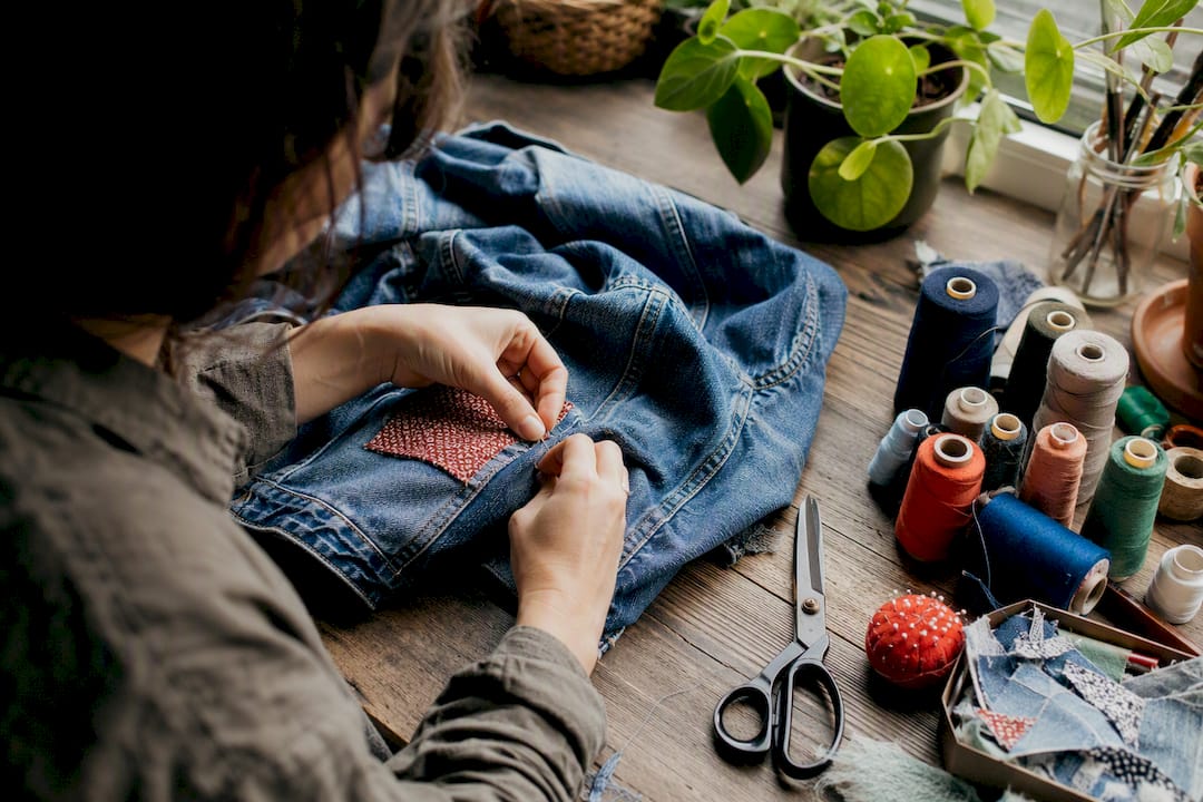 Hands sewing denim jacket patch