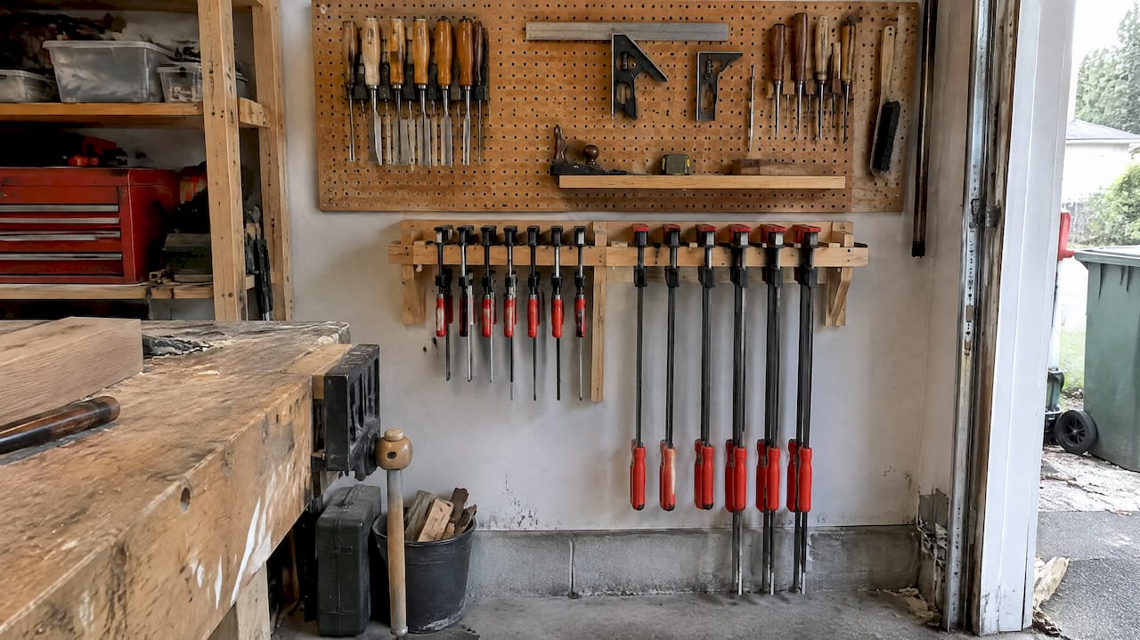 Skip the Table Saw: Buy Order for Beginner Woodworking Tools in Canada 2026 Lizard's Lunch Pegboard and clamp rack in garage workshop
